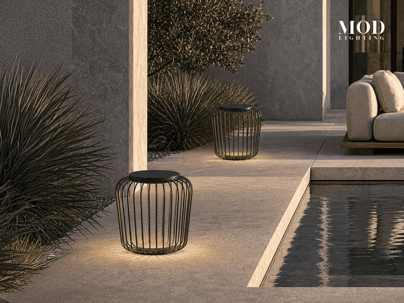 Cedar black wire-cage lanterns lit along a stone terrace beside a reflecting pool at dusk
