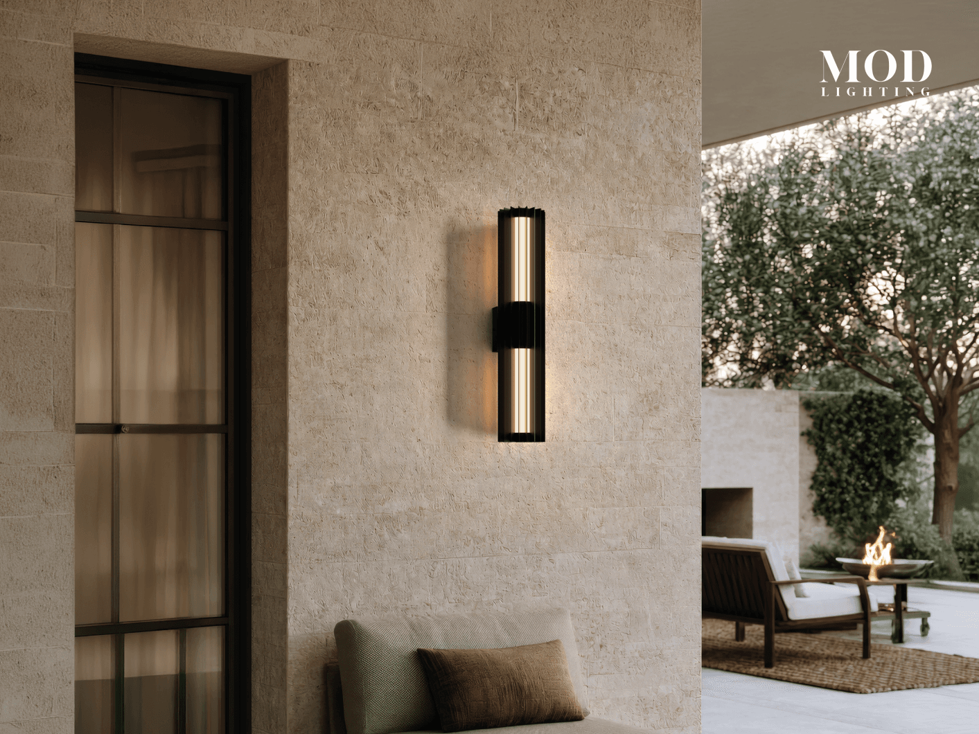 Knox black outdoor sconce, ribbed glass cylinder glowing up and down on a travertine wall above a patio
