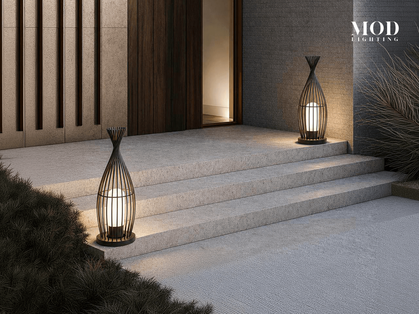 Cove black cage lanterns lit on either side of stone entry steps at night
